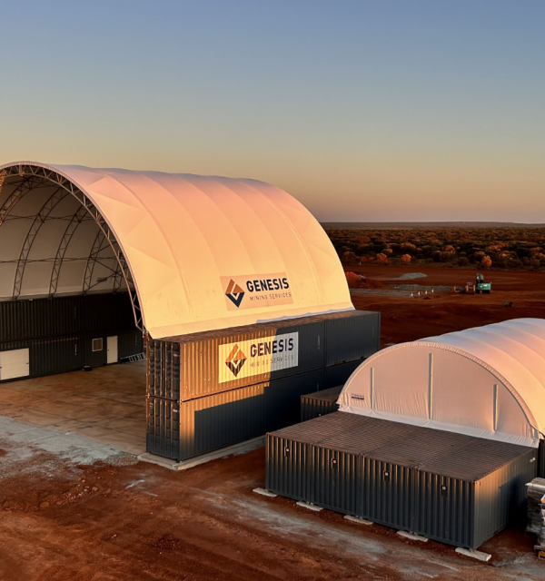 Two Genesis Mining Services-branded DomeShelter™ structures on stacked containers in a remote, red-dirt industrial setting at sunset.